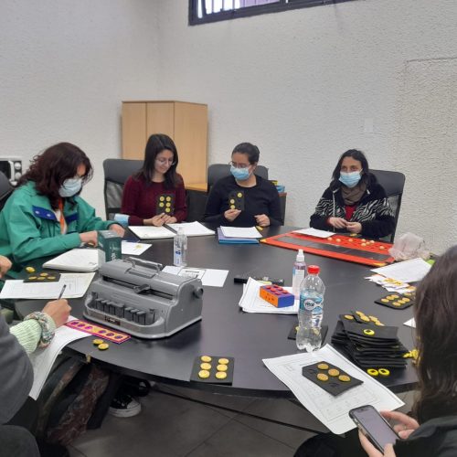 Fotografia en la que aparecen 5 personas realizan un taller de escritura en Braille